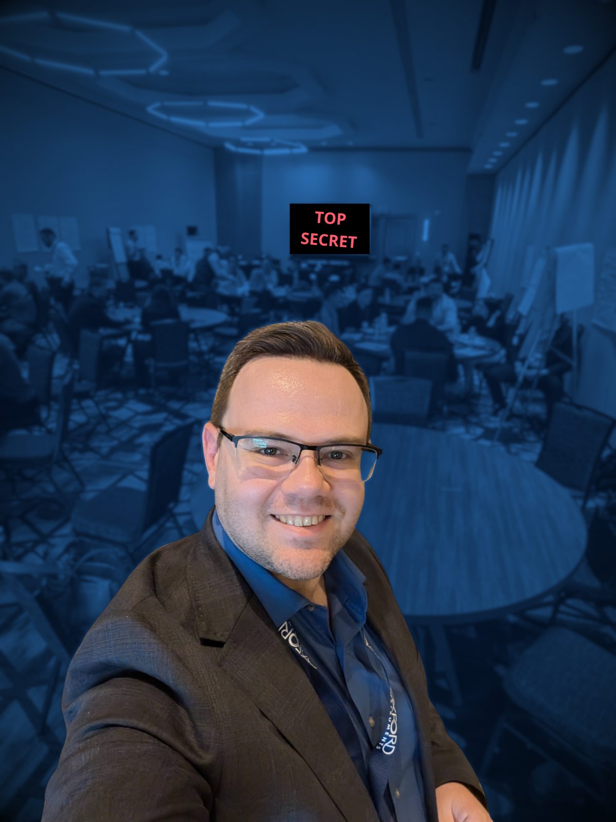 Alexei Kazarine presenting at a company meeting, the room behind him blurred and the projector screen stamped top secret